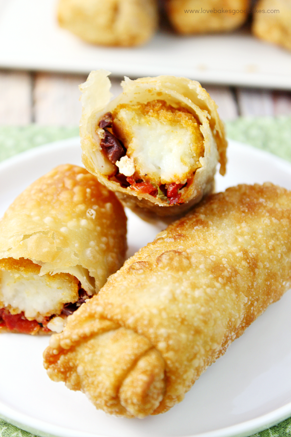 Cheesy Mediterranean Egg Rolls stacked up on a plate.