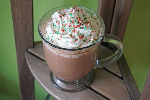 A pick-me-up peppermint mocha in a glass mug, resting on the top of a tiered wooden plant stand